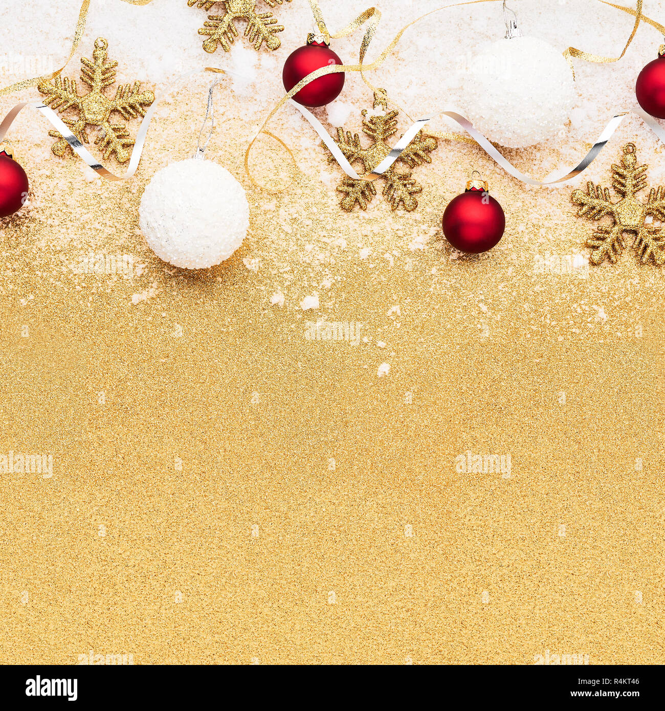 Beautiful christmas red, white and gold deco baubles with powdery snow on golden glitter background. Flat lay design. Copy Space. Square crop. Stock Photo