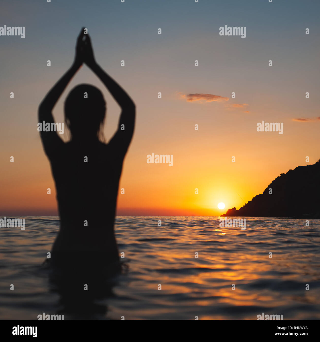 yoga pose woman sunset silhouette in sea. Ocean bathing at sun dawn Stock Photo