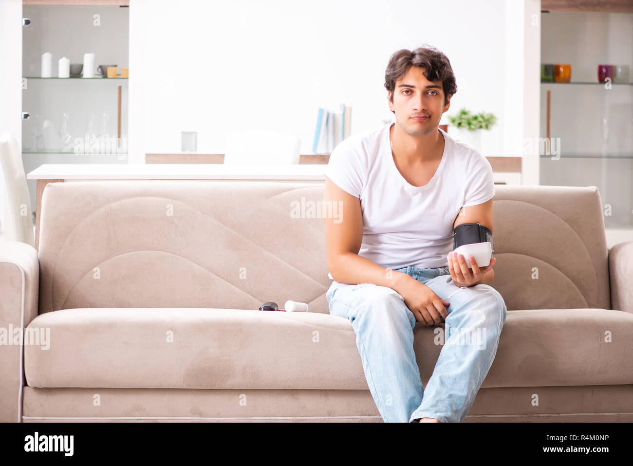 Young man measuring blood pressure at home Stock Photo - Alamy