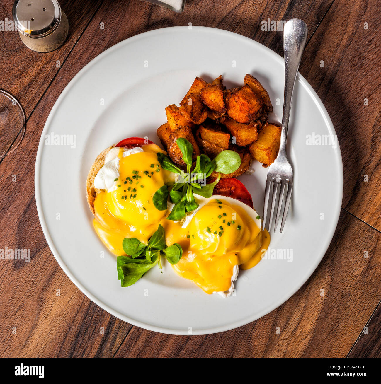 Eggs Benedict is a traditional American breakfast or brunch dish  with bacon, ham, a poached egg, and hollandaise sauce. Stock Photo