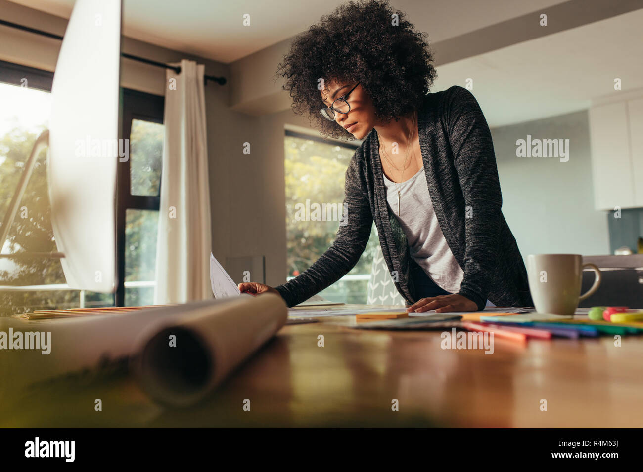 Female designer working on a new project. Woman with curly hair reviewing a design at home office. Stock Photo