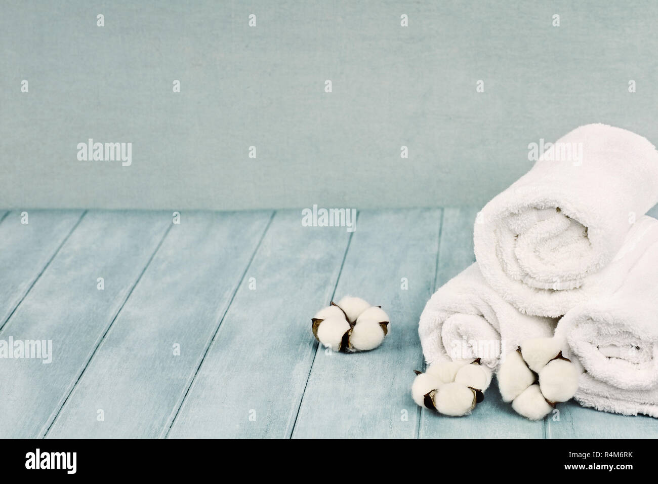 Rolled up white fluffy towels with cotton flowers against a blurred blue  background with free space for text Stock Photo - Alamy
