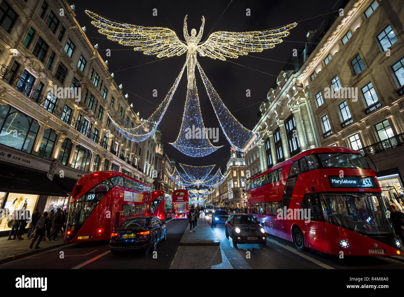 Busy holiday shopping scene with double decker buses and black cabs zooming past pedestrians on a winter night on Regent Street, London Stock Photo