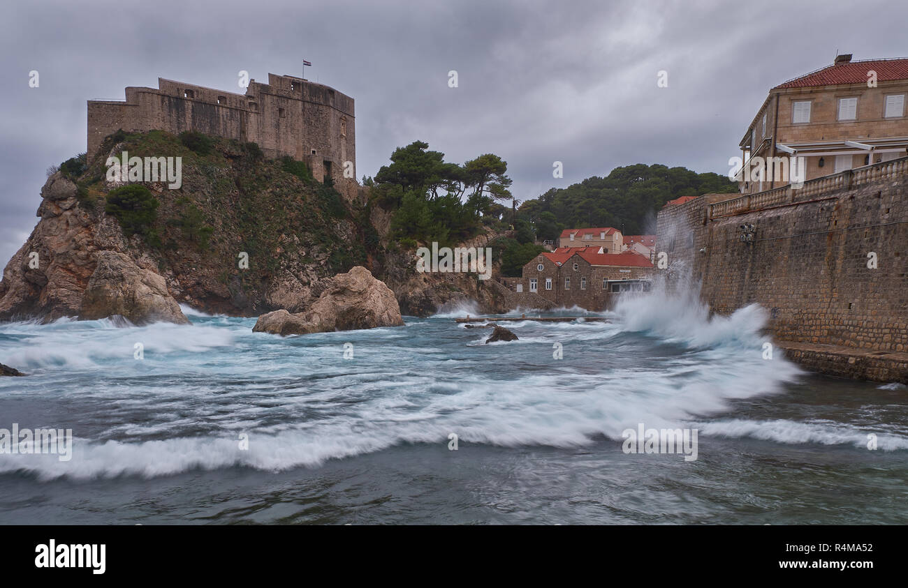 Fort Lovrijenac in Dubrovnic as seen from the beach on a stormy day, with crashing waves and dark clouds. Stock Photo