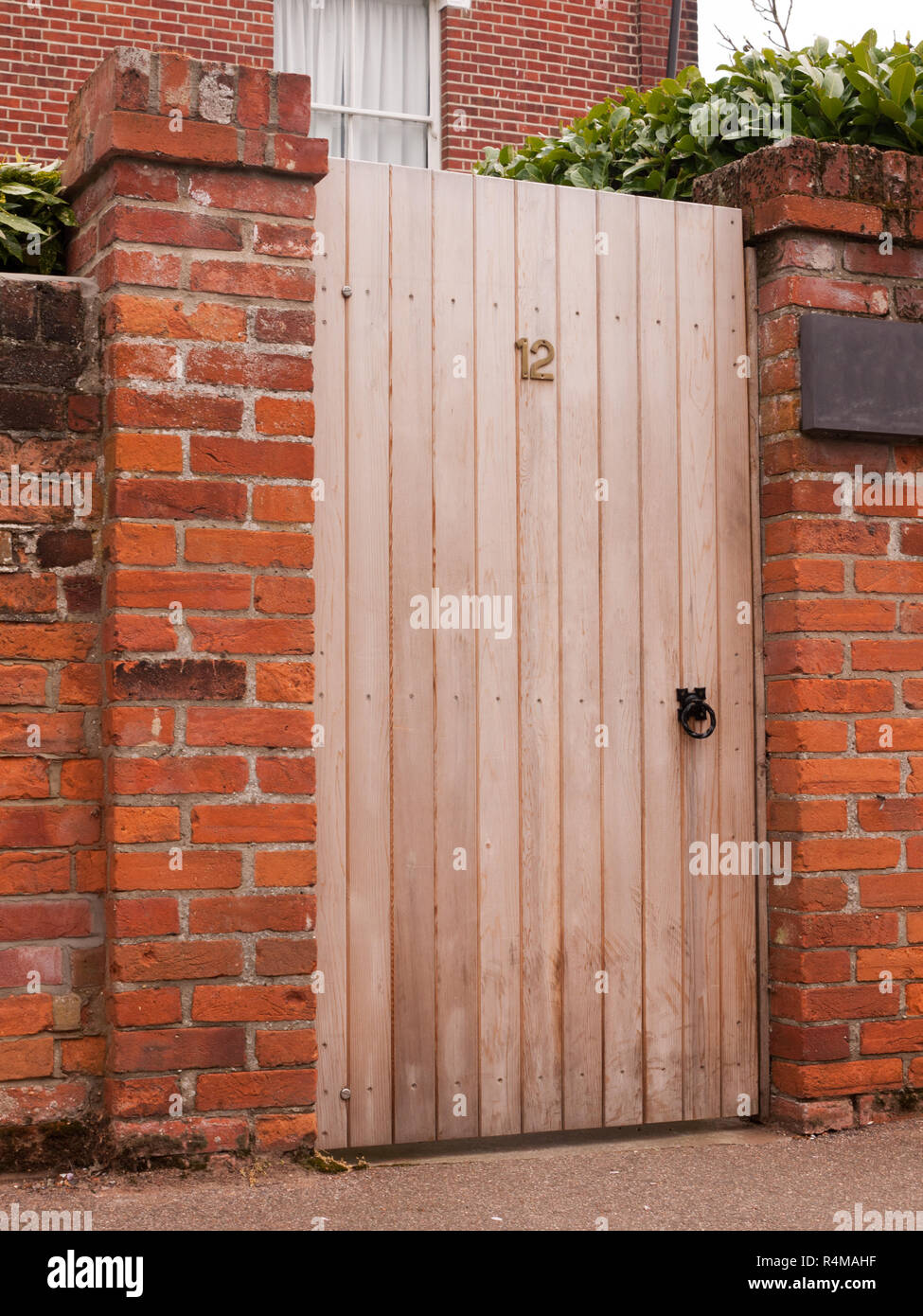 a wooden door outside closed with the number 12 on it and attached to a high wall on a house Stock Photo