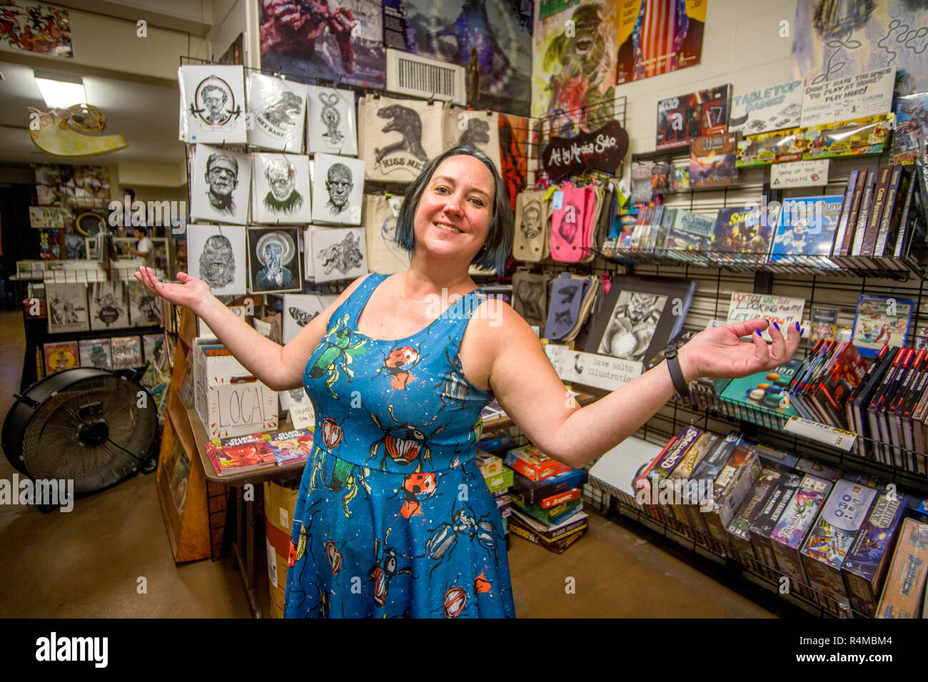 The proprietor of a comic book art shop in Fullerton, CA, proudly shows off display racks of her inventory. Stock Photo