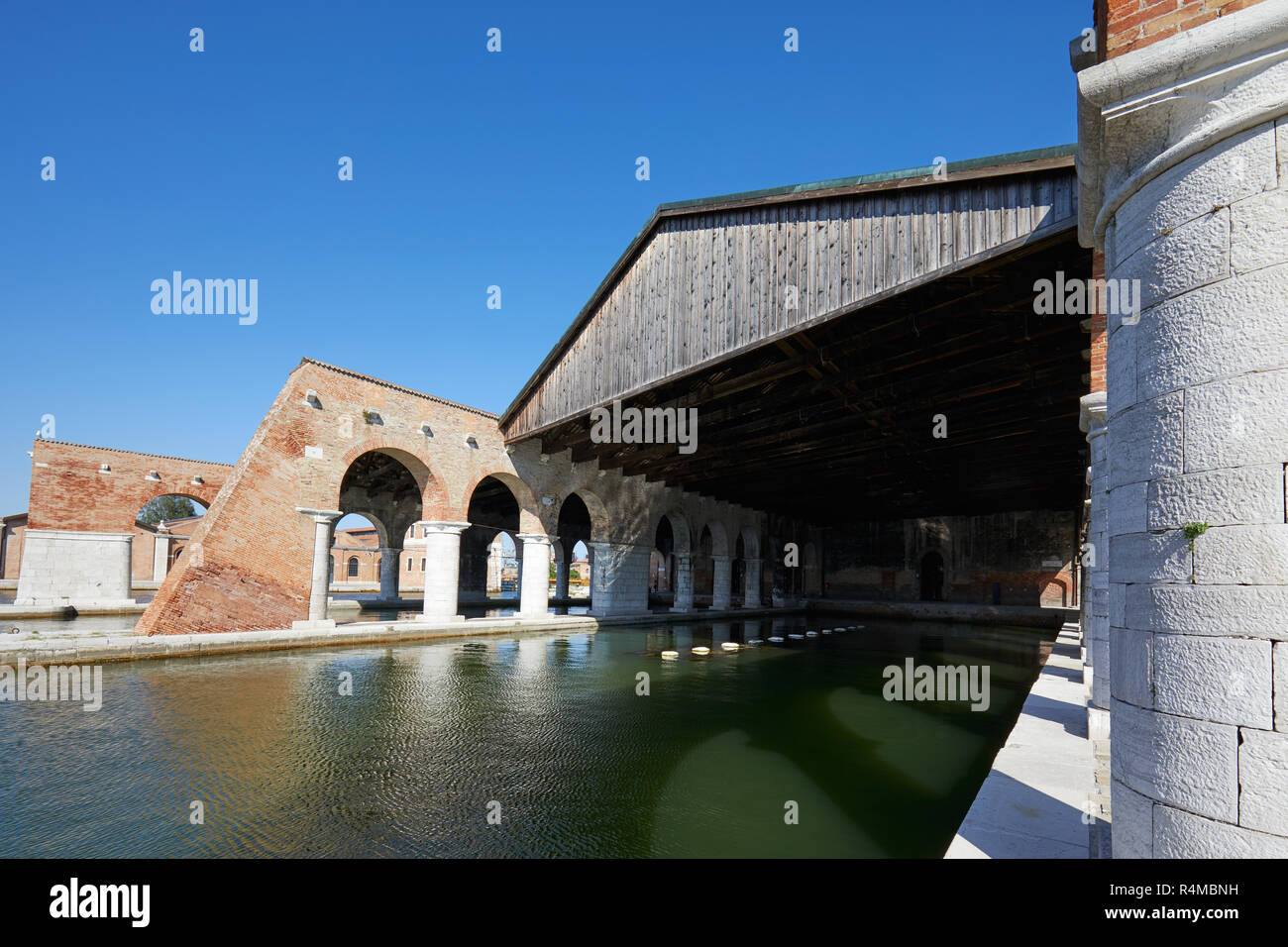 Venetian Arsenal with docks, wide canal and arcade, blue sky in Venice, Italy Stock Photo