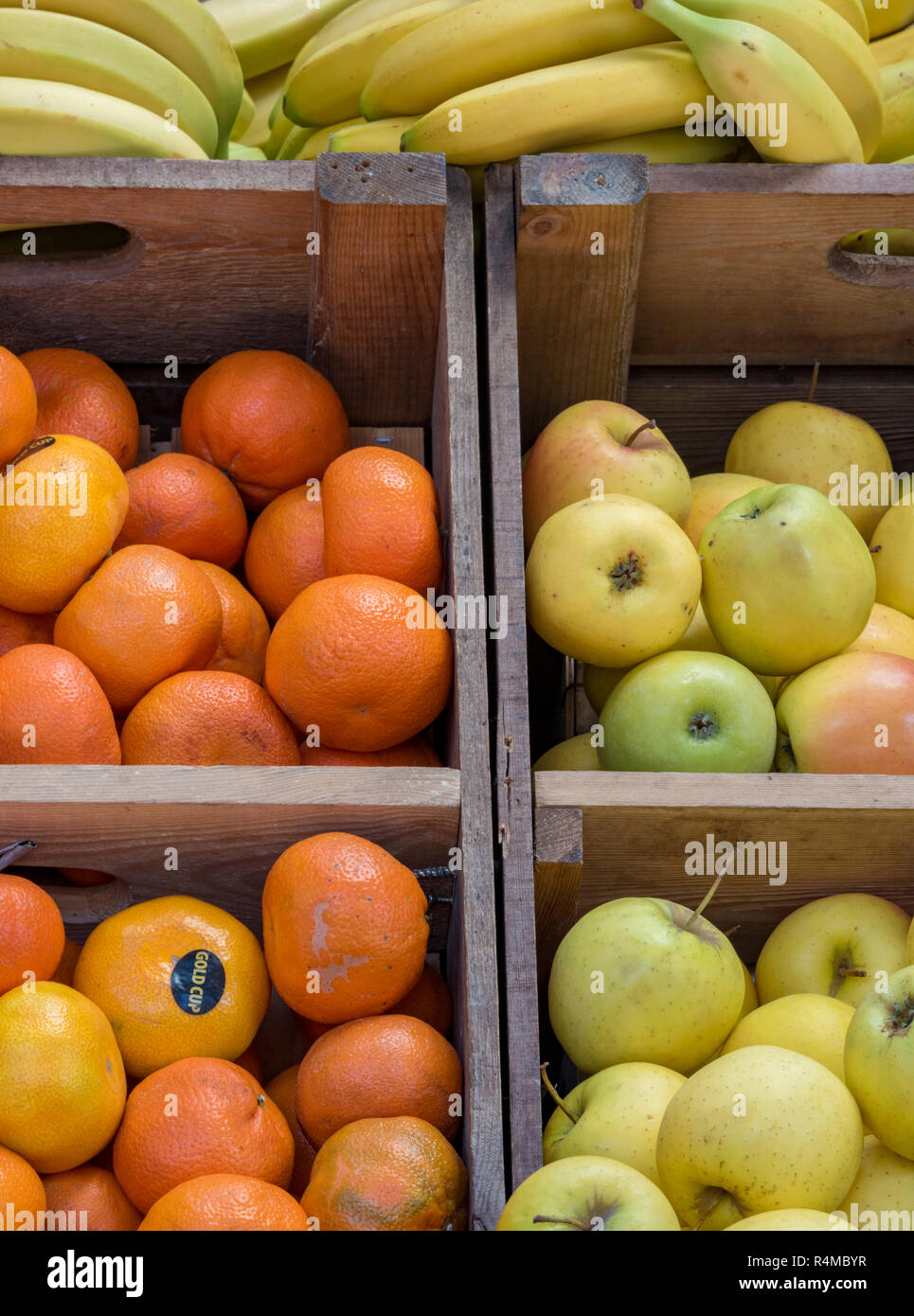 apples, oranges and bananas on sale on a greengrocers stall at a market selling fresh fruits and
