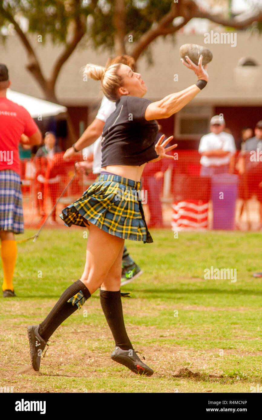 Kilt and crested T-shirt fly as a grimacing contestant prepares to toss the 16-pound Braeman Stone at Highland Games in Costa Mesa, CA. Stock Photo