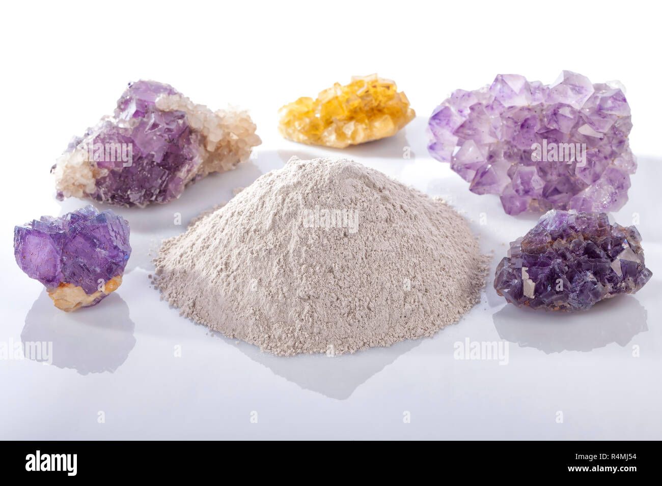 A pile of processed fluorine powder spar surrounded by mineral fluorite stones isolated on white. Stock Photo