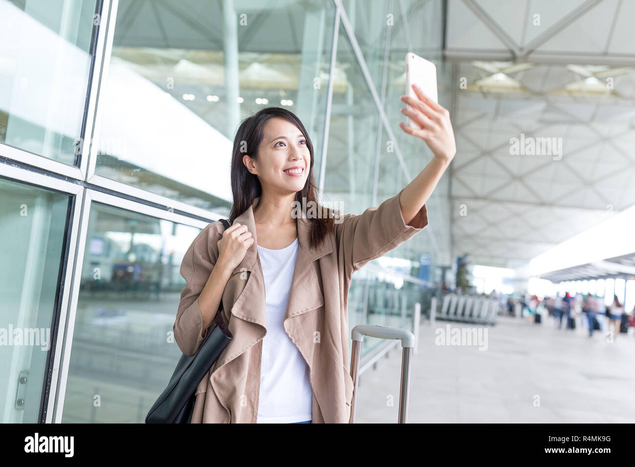 Woman taking selfie by mobile phone in hong kong international airport ...