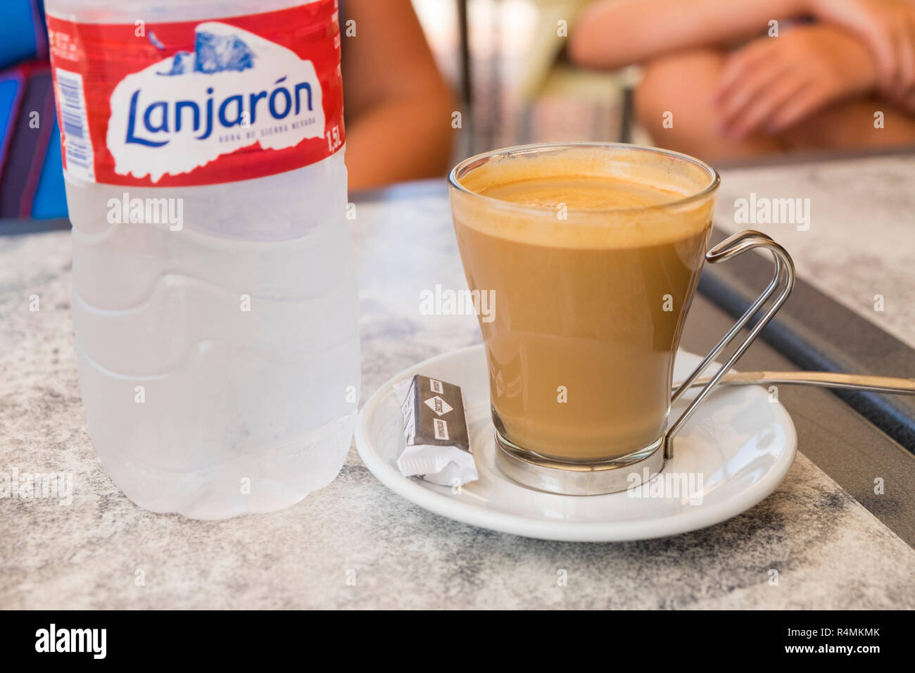 Glass coffee cup with wire handle and a bottle of lanjaron water