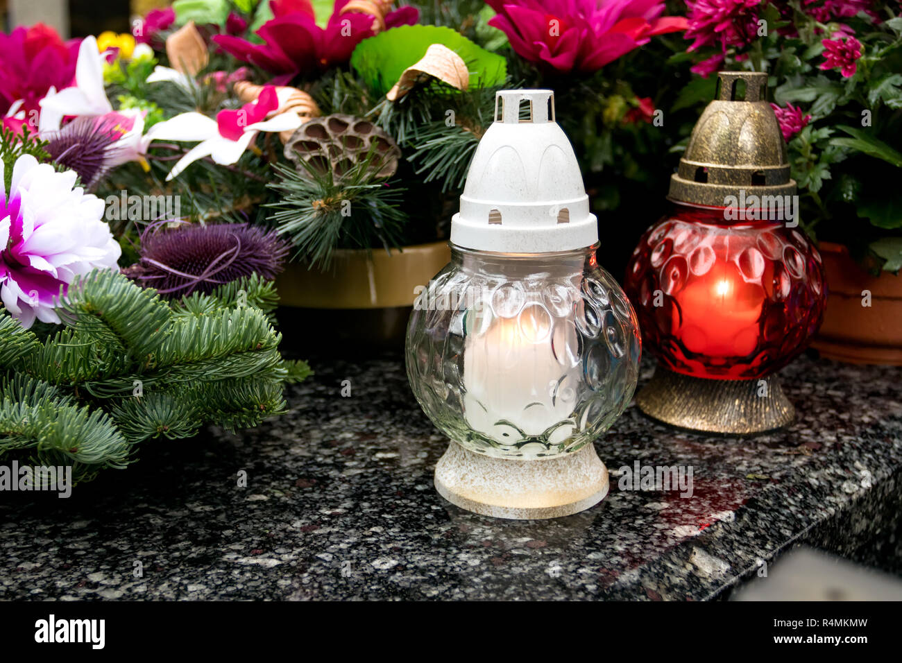 White and red cemetery candle lights and flowers on a grave. All saints