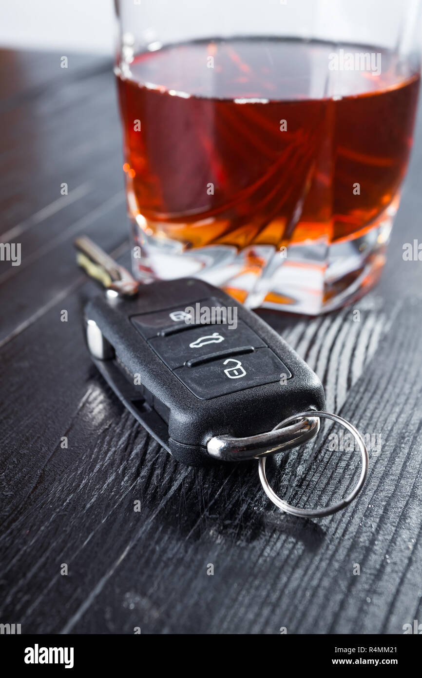 Car key and whiskey alcohol drink in a glass on black wooden table. Don ...