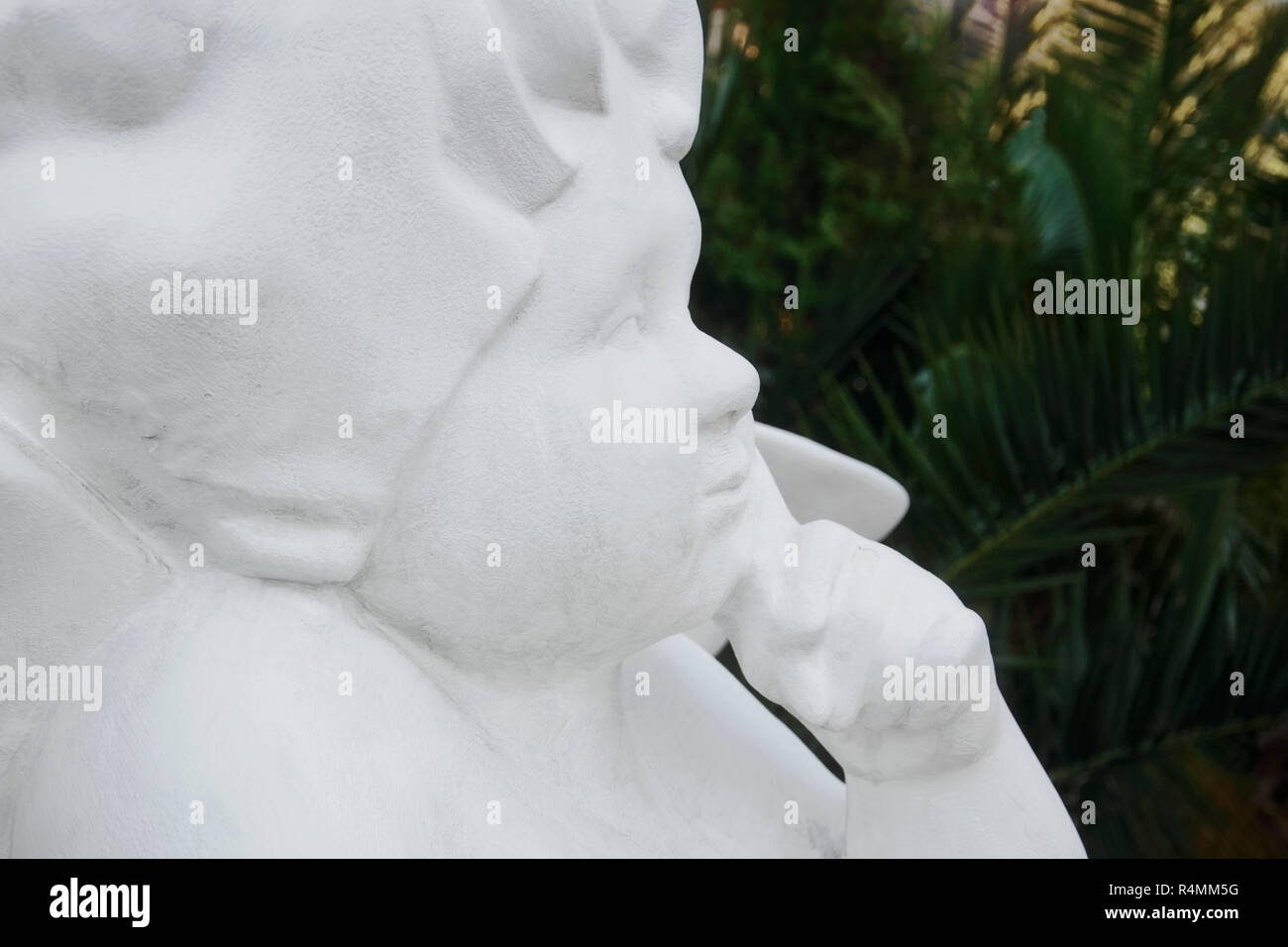 White statue of the angel against the background of palm trees Stock Photo