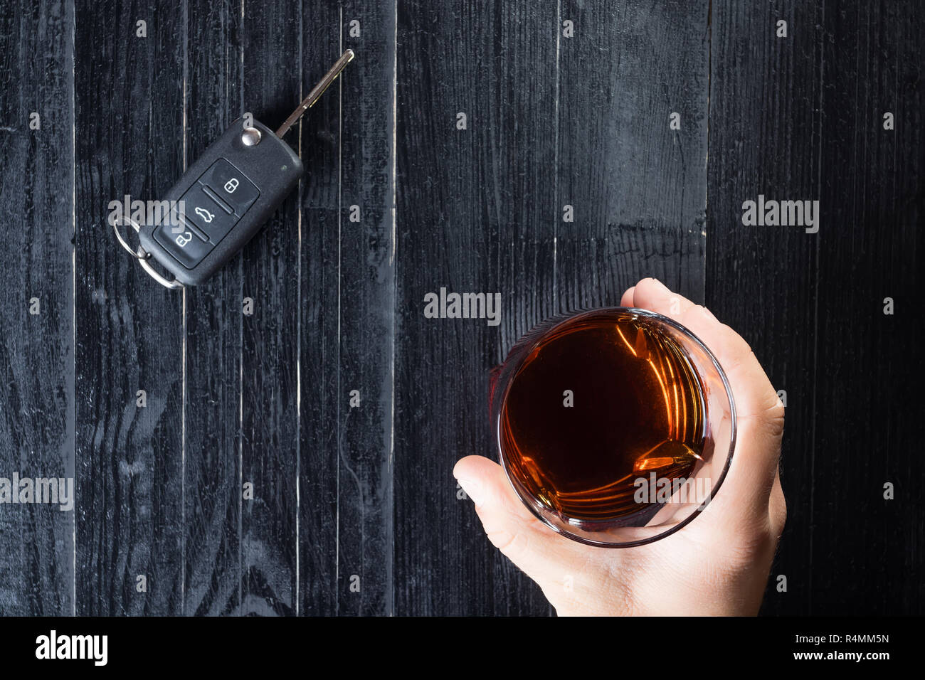Car key and whiskey alcohol drink in a glass on black wooden table. Don ...