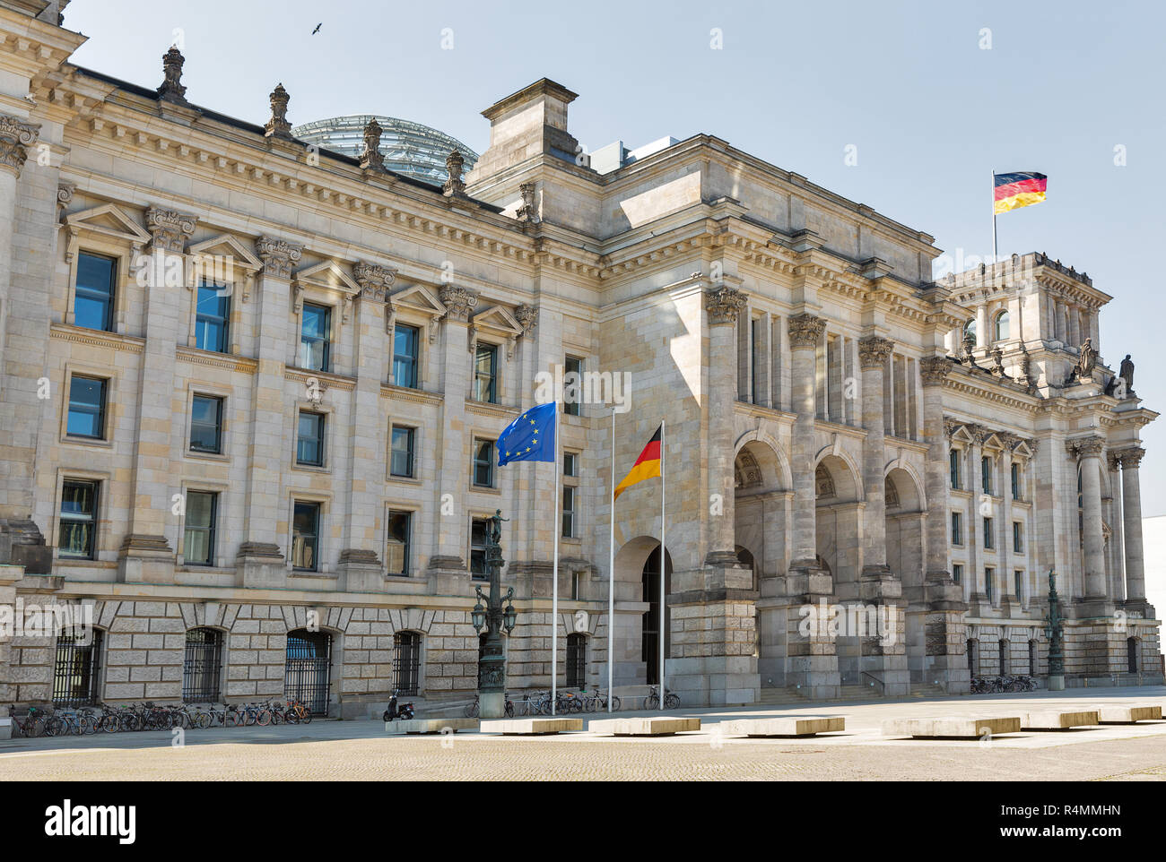 Parked bicycles in front of famous Reichstag or Bundestag building with German and EU flags, seat of the German Parliament. Berlin Mitte district, Ger Stock Photo
