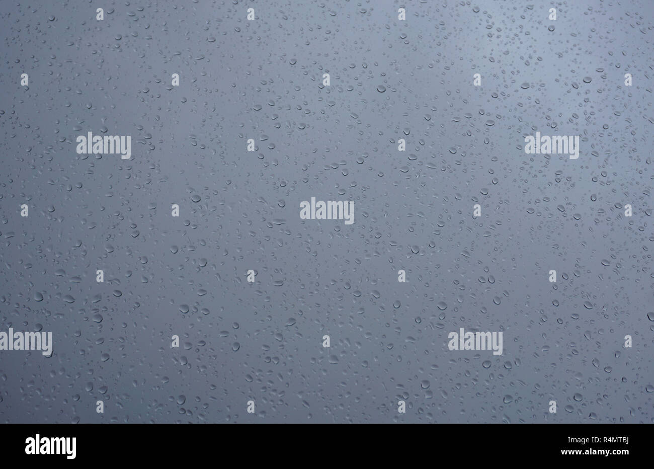 Dark blue window glass surface with rain drops on it. Water drips texture background Stock Photo