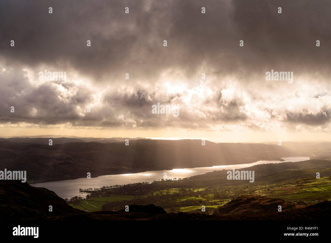 Coniston Water illuminated by crepuscular rays viewed from the lower slopes of Wetherlam Stock Photo