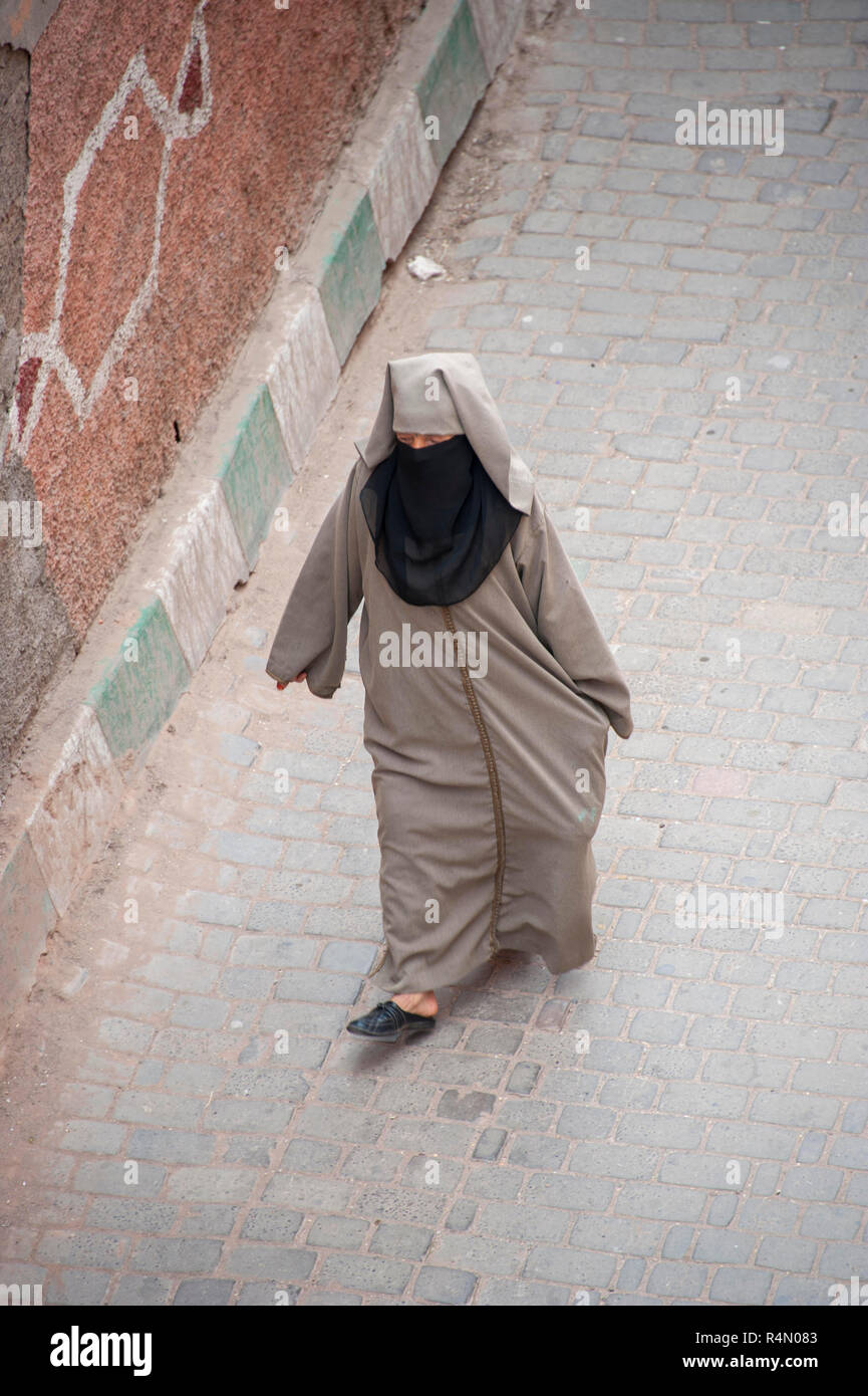 18-04-11. Marrakech, Morocco.  A street scene in the medina photographed from above. A woman in traditional dress of a hajib and scarf walks down the Stock Photo