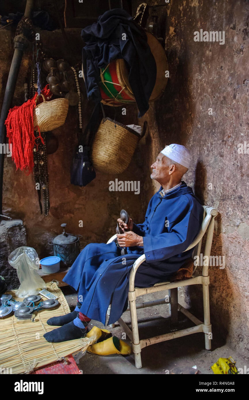 18-04-11. Marrakech, Morocco.  An elderly man dressed in traditional clothes and a skull cap, plays krakebs,  large iron castanet-like musical instrum Stock Photo