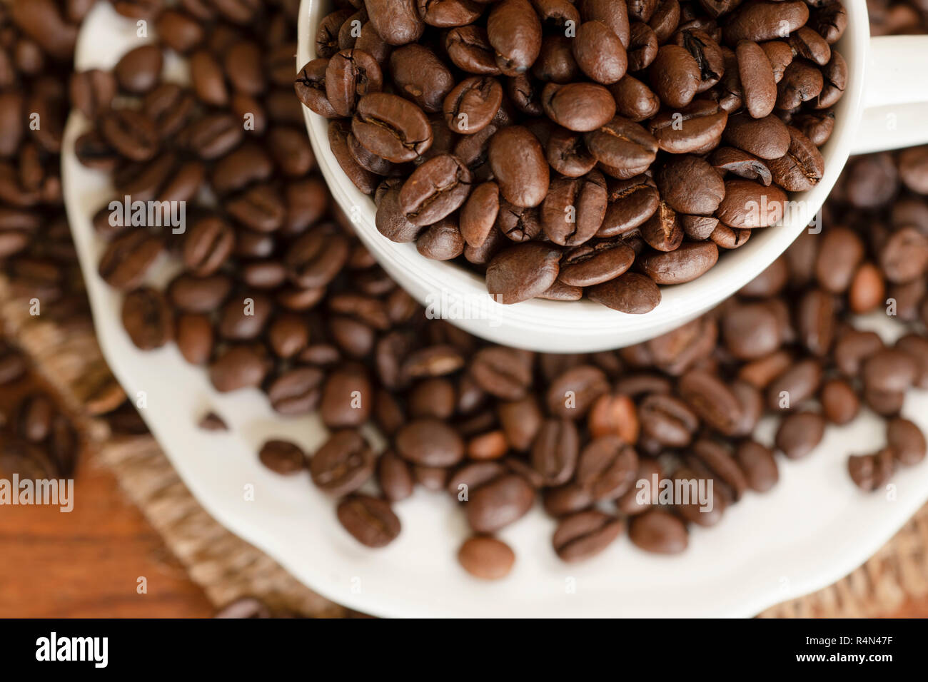 Coffee beans in cup and saucer Stock Photo Alamy