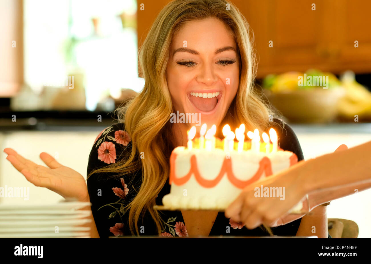 Surprised young woman receiving birthday cake Stock Photo