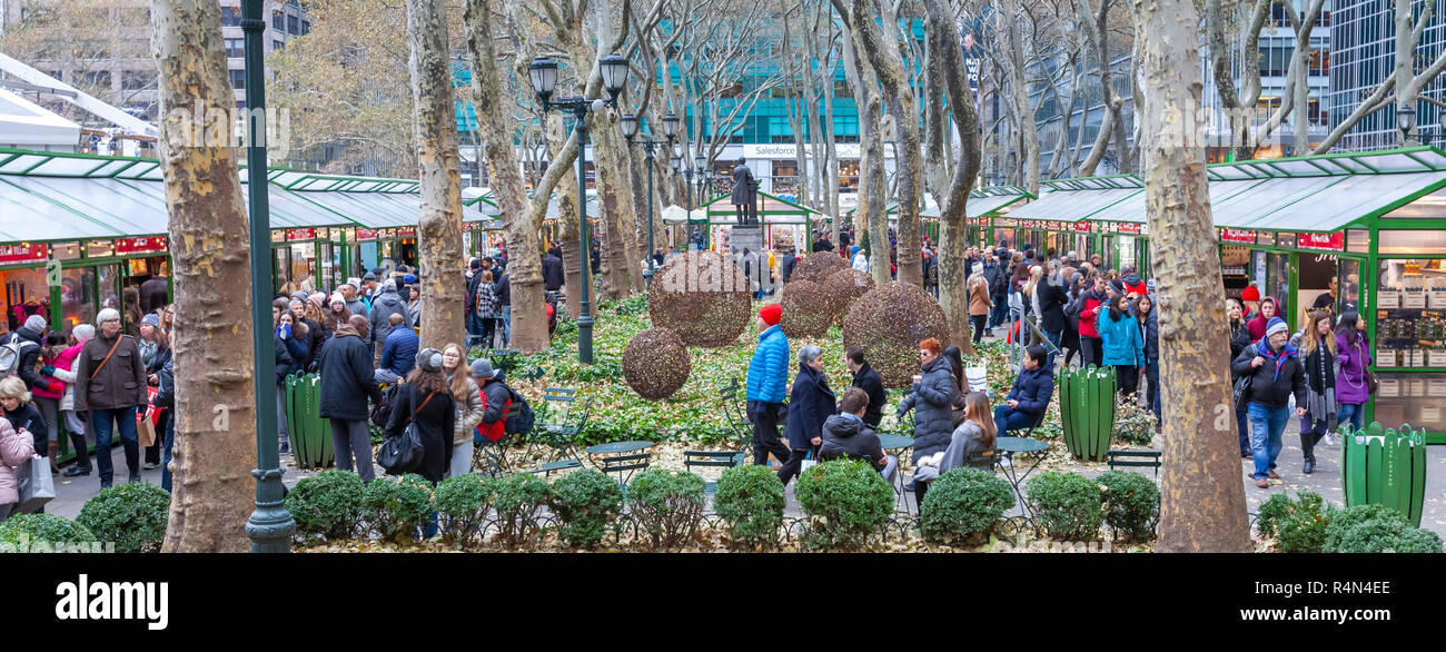 Families and friends of all ages enjoy shopping in the Christmas Village Shops in the Winter Village at Bryant Park, Manhattan, New York City. Stock Photo