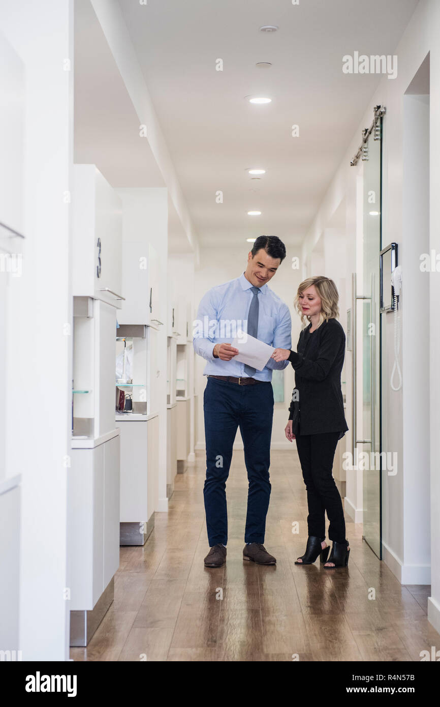 Dentist and dental nurse discussing notes in corridor Stock Photo
