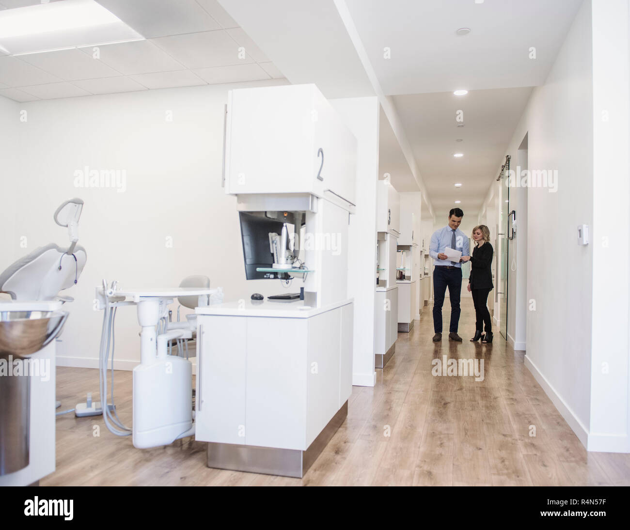 Dentist and dental nurse discussing notes in corridor Stock Photo