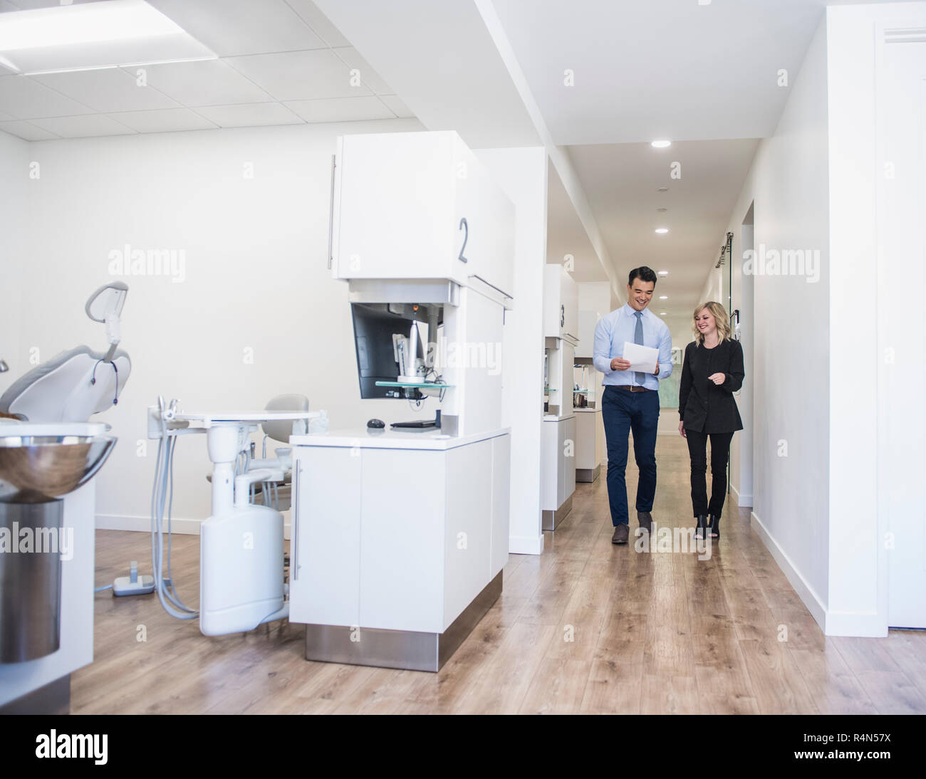 Dentist and dental nurse discussing notes in corridor Stock Photo