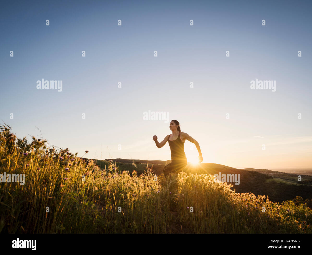 Mid adult woman jogging at sunset Stock Photo