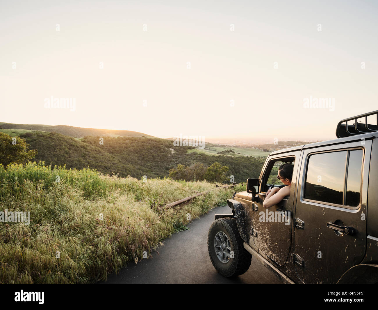 Woman in off road vehicle looking at sunset Stock Photo
