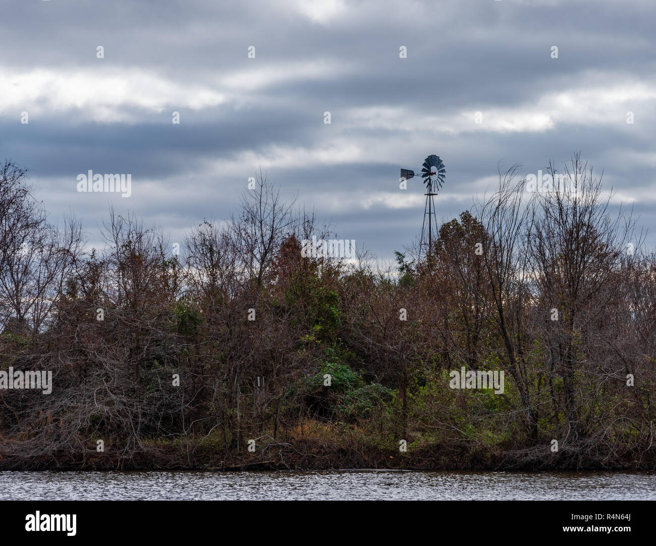 A solitary windmill stands in a field on a cold, windy and overcast  day. Stock Photo