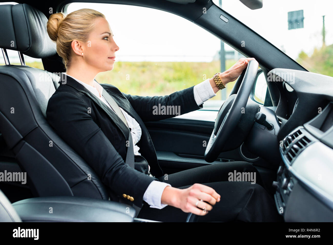 Woman driving in her car in business attire Stock Photo - Alamy