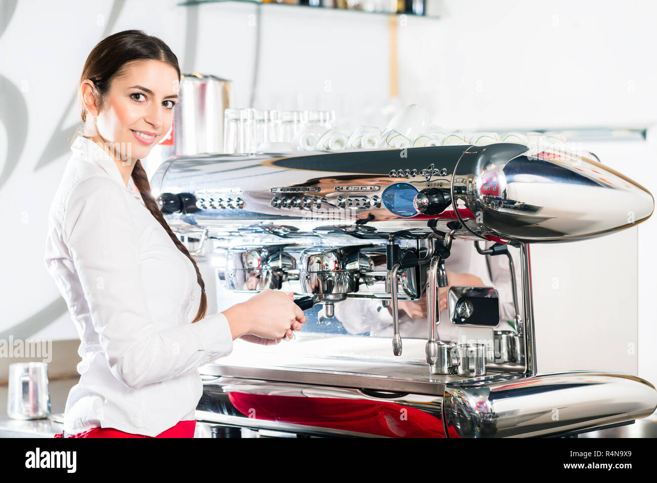 Young waitress using an automatic coffee machine Stock Photo