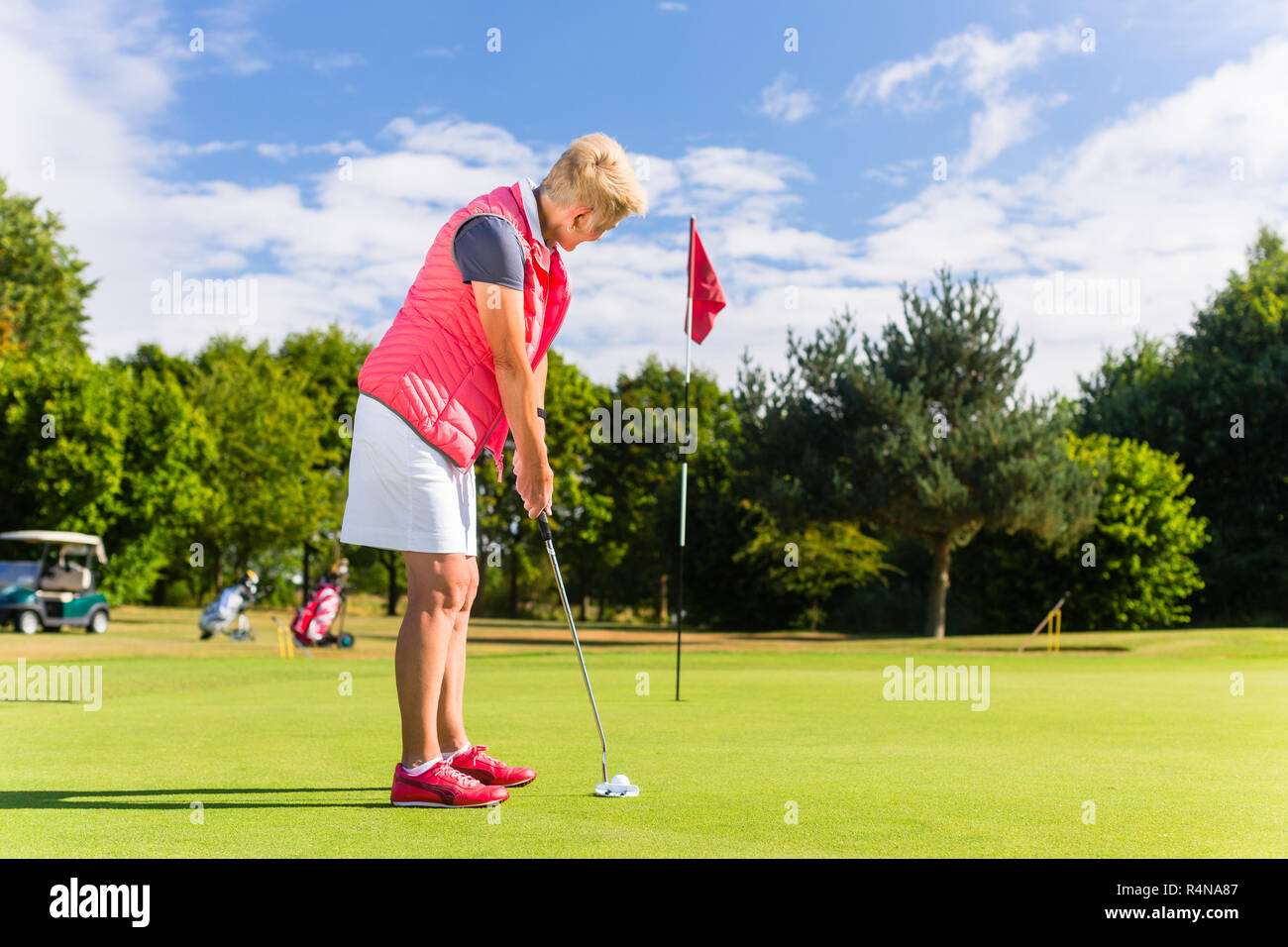 Senior golf playing woman putting on green Stock Photo