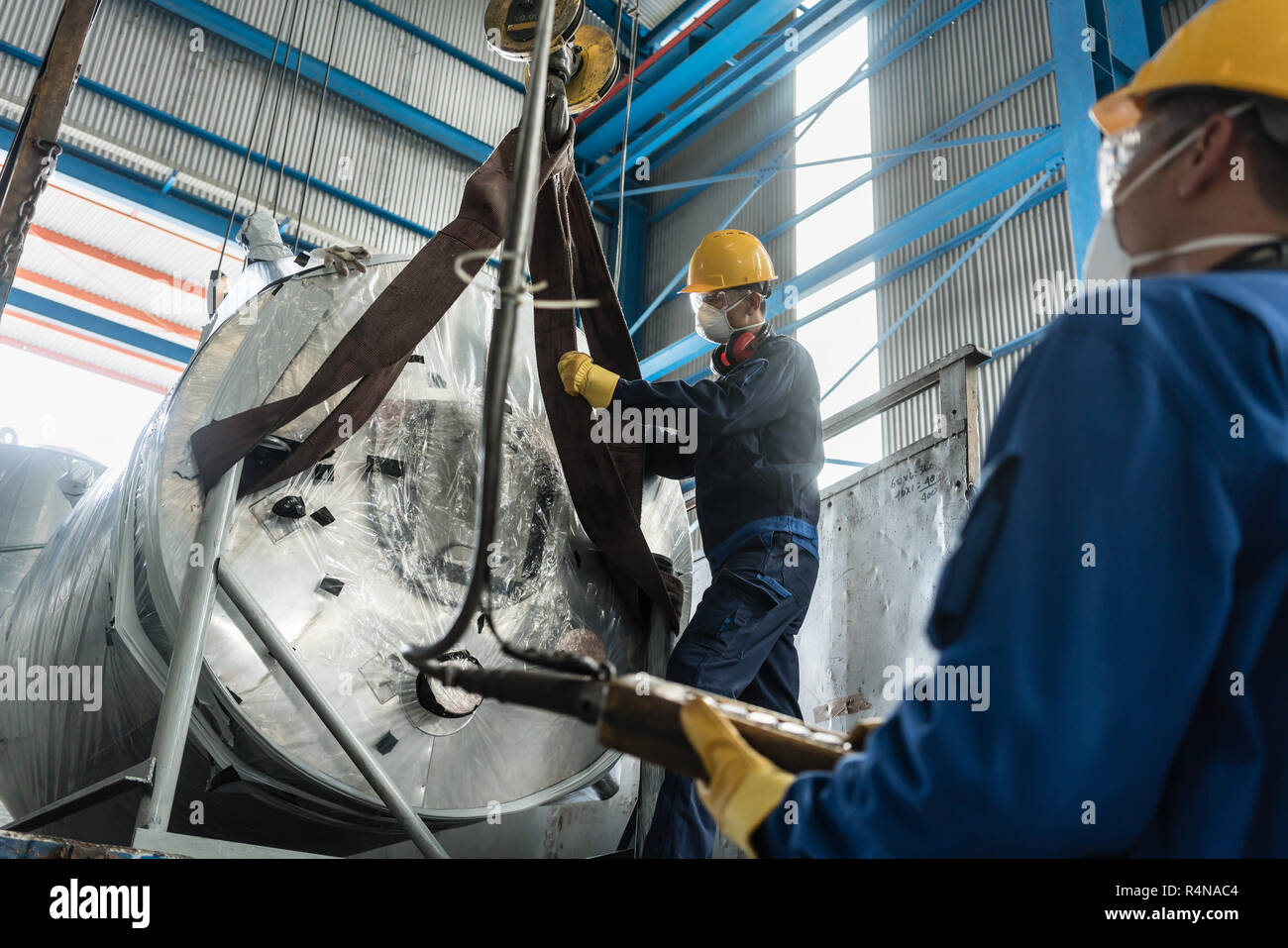 Workers handling equipment for lifting industrial boilers Stock Photo