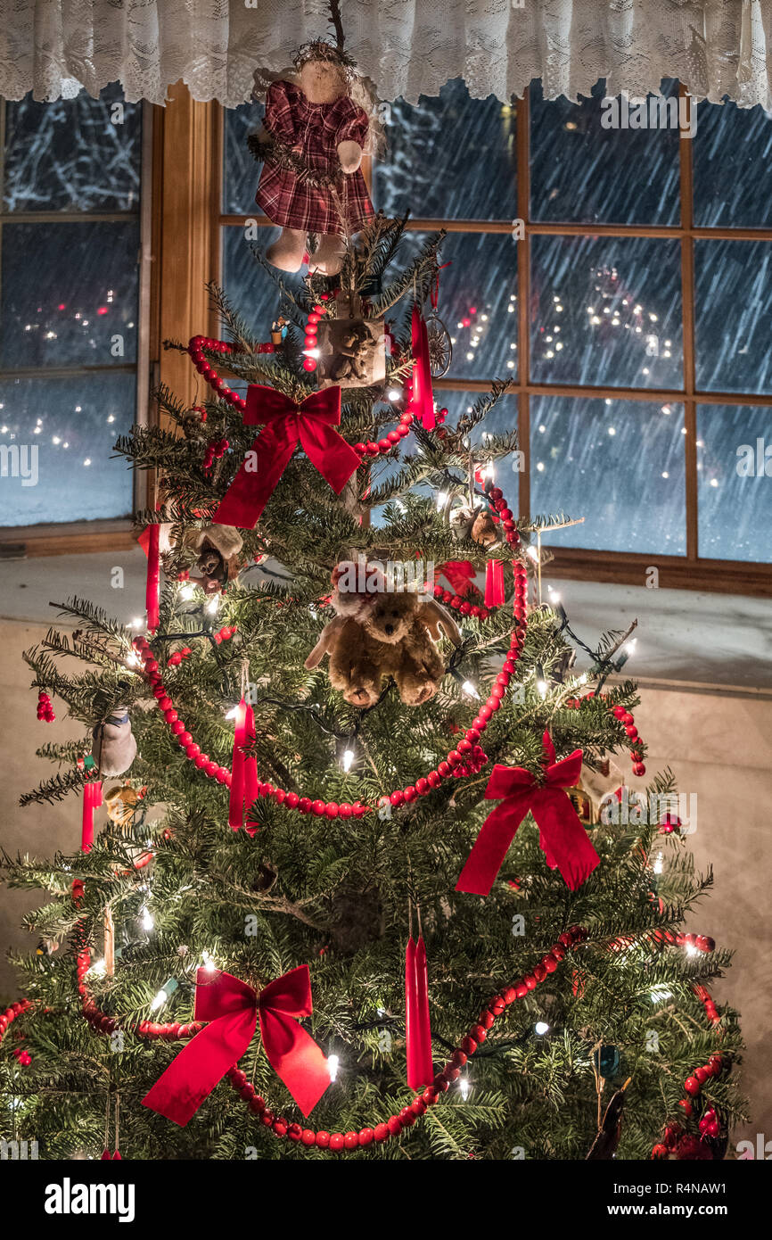 A decorated Christmas tree and snowing outside Stock Photo