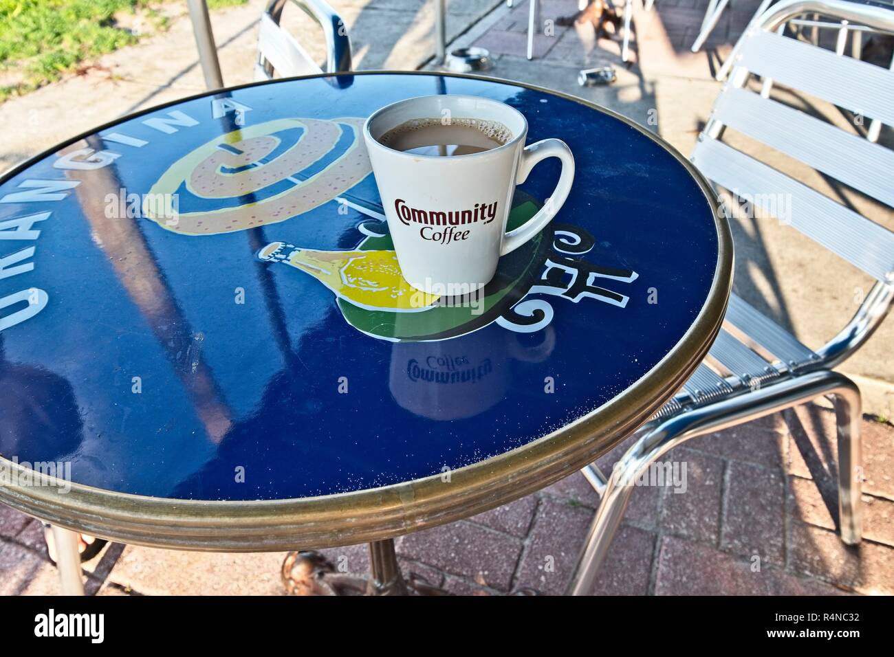 Coffee cup with Community Coffee logo filled with coffee and cream sitting on empty patio table at Camille's in Crystal Beach Florida, USA. Stock Photo