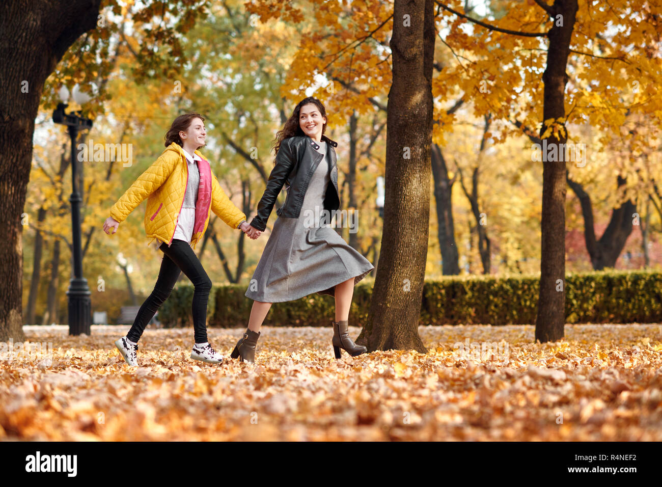 Two happy girls running in autumn city park Stock Photo - Alamy