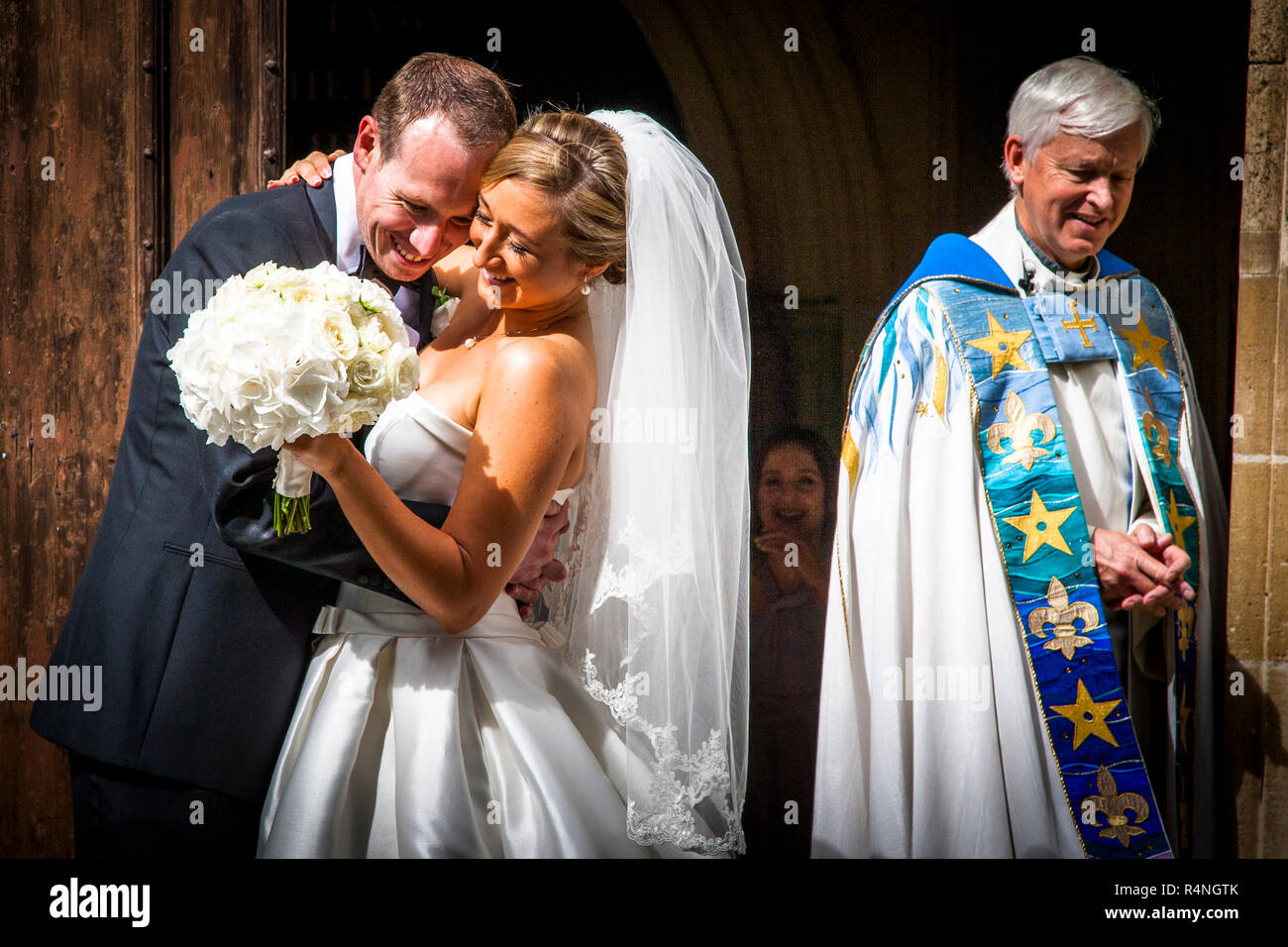Happiness and satisfaction. After the Wedding the couple and the vicar are smiling Stock Photo