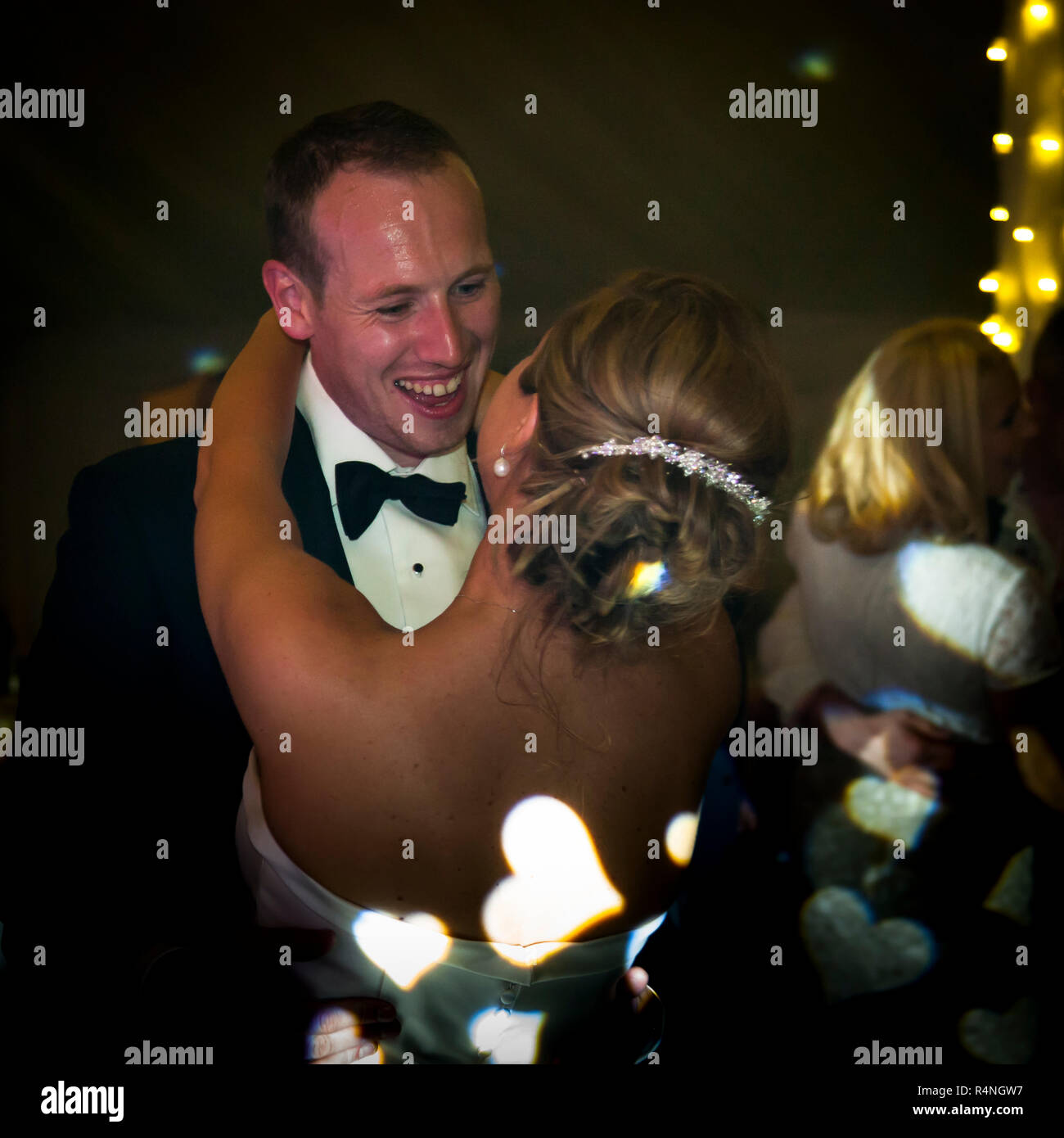 Bride and groom on dance floor with projection of hearts on bride's back Stock Photo