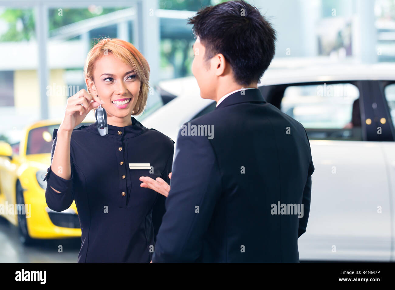 Asian man at car rental receiving key Stock Photo
