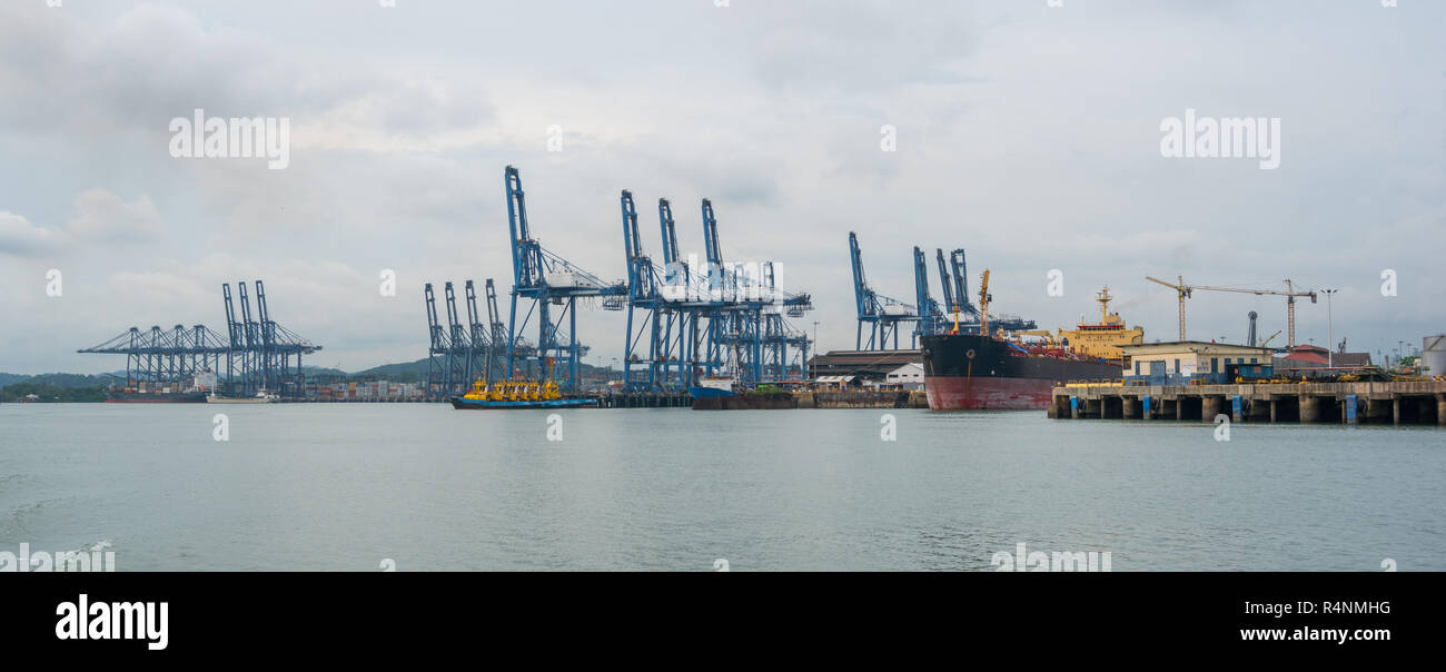 Container cranes loading a ship in port in Panama near the entrance to the Panama Canal. Stock Photo