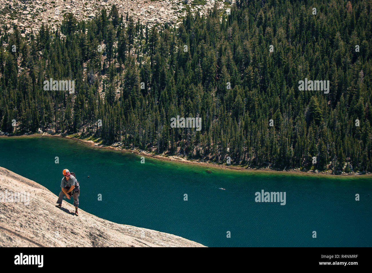 View of single adventurous man rock climbing above lake inÂ TuolumneÂ Meadows, Yosemite National Park, California, USA Stock Photo