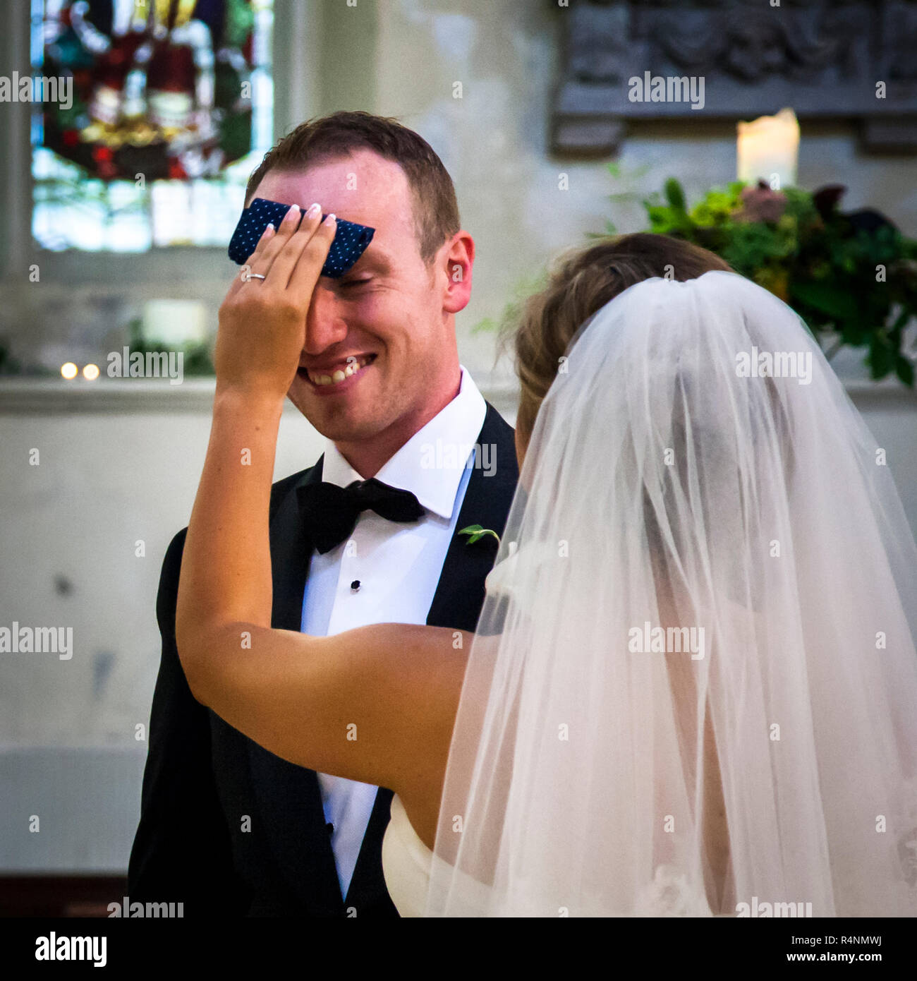 During Wedding in church, the bride dries the grooms forehead with a tissue Stock Photo