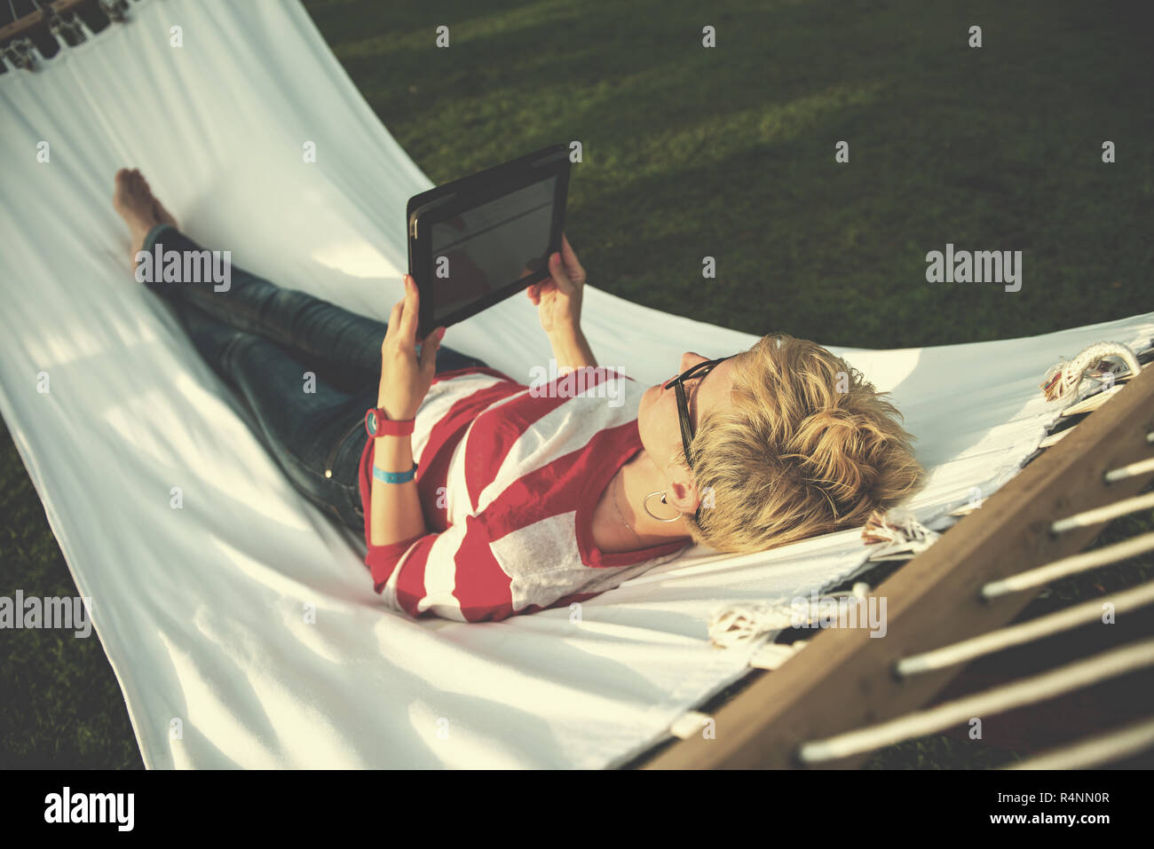 young woman using a tablet computer while relaxing on hammock in a ...
