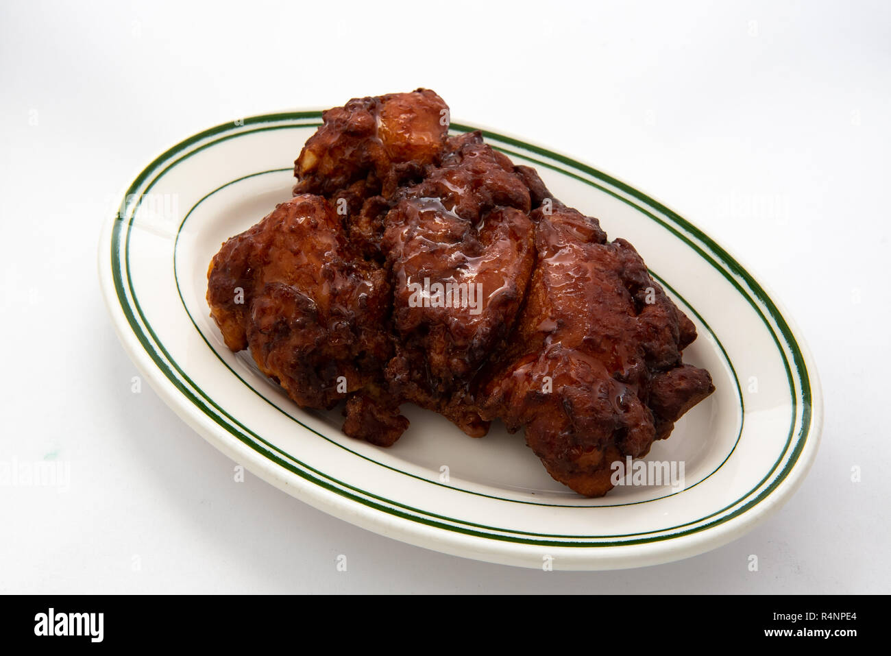 A glazed apple fritter on a white plate with a white background. Stock Photo