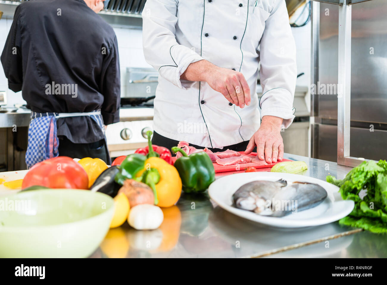 Chef putting salt on fish while cooking in kitchen Stock Photo Alamy